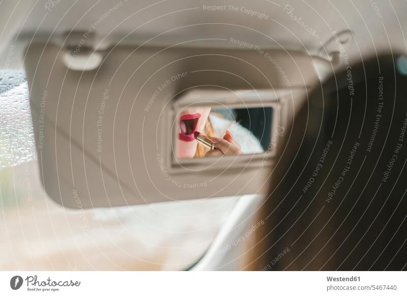 Im Rückspiegel gespiegelte Frau trägt im Auto roten Lippenstift auf roter rotes Lippenstifte anwenden auftragen Wagen PKWs Automobil Autos weiblich Frauen
