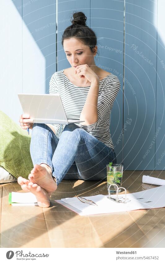 Frau sitzt am Fenster zu Hause arbeiten mit Laptop und Dateiordner sitzen sitzend weiblich Frauen Arbeit Notebook Laptops Notebooks Zuhause daheim Aktenordner