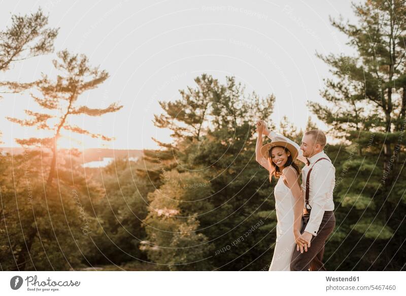 Braut und Bräutigam tanzen bei Sonnenuntergang im Wald Farbaufnahme Farbe Farbfoto Farbphoto Außenaufnahme außen draußen im Freien Sonnenuntergänge Stimmung