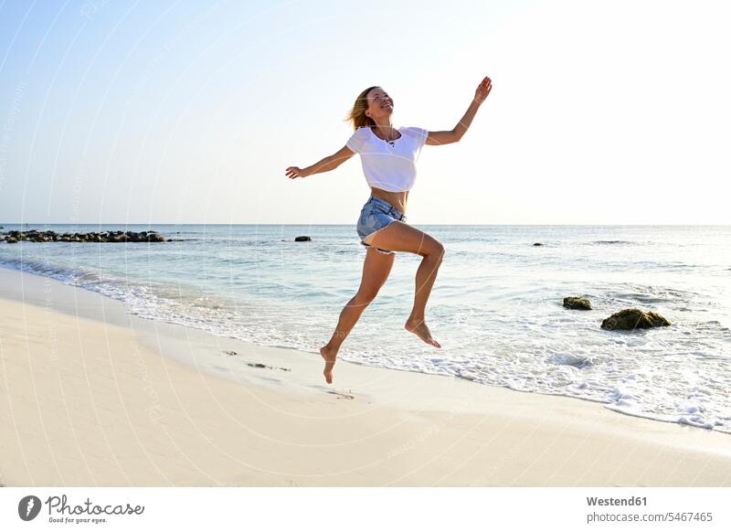 Schöne Frau rennt und springt vor Freude am Strand rennen freuen Frohsinn Fröhlichkeit Heiterkeit Glück glücklich sein glücklichsein Dynamik dynamisch Power