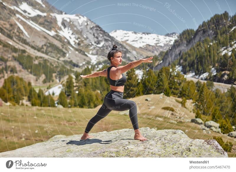 Junge Frau macht Yoga stehend auf Felsen in der Natur, Krieger-Pose junge Frau junge Frauen Balance ausgeglichen Ausgeglichenheit Gleichgewicht Textfreiraum