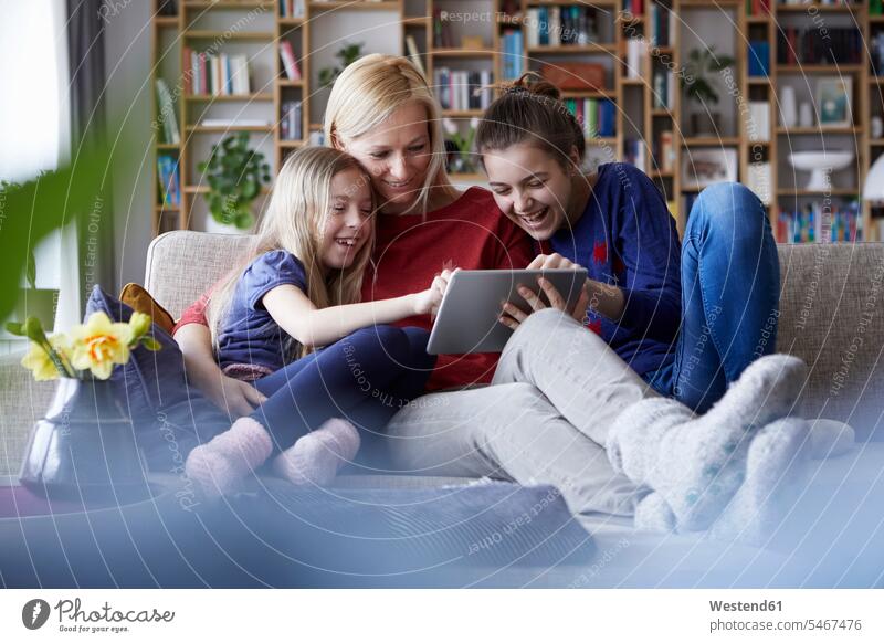Mutter und ihre Töchter sitzen auf der Couch und haben Spaß mit einem digitalen Laptop Sofa Couches Liege Sofas Tablet Tablet Computer Tablet-PC Tablet PC iPad