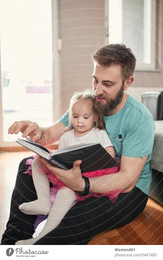 Vater und Tochter lesen ein Buch hoeren knuddeln schmusen Lektüre sitzend sitzt freuen innig nah daheim zu Hause Muße Miteinander Zusammen Individuell vertrauen