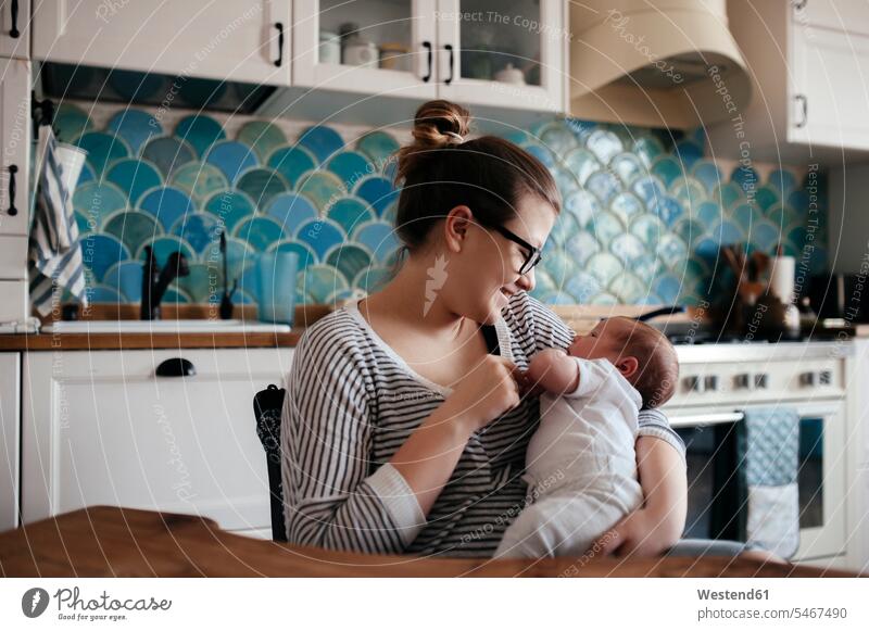 Porträt einer jungen Frau mit einem Baby zu Hause Brillen knuddeln schmusen sitzend sitzt friedfertig friedlich friedliebend behüten behütet geborgen Sicherheit