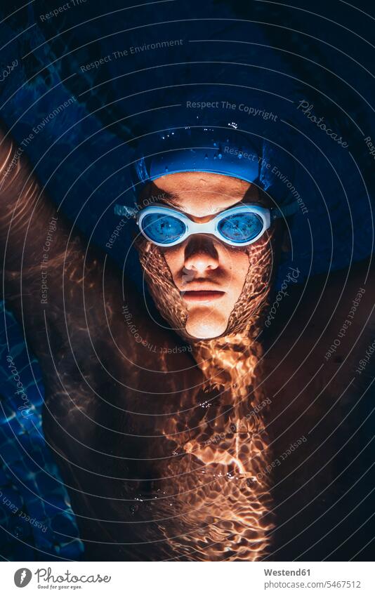 Porträt eines jungen paralympischen Schwimmers, der in einem Schwimmbecken auf dem Wasser schwimmt Farben Farbtoene Farbton Farbtöne blaue blauer blaues