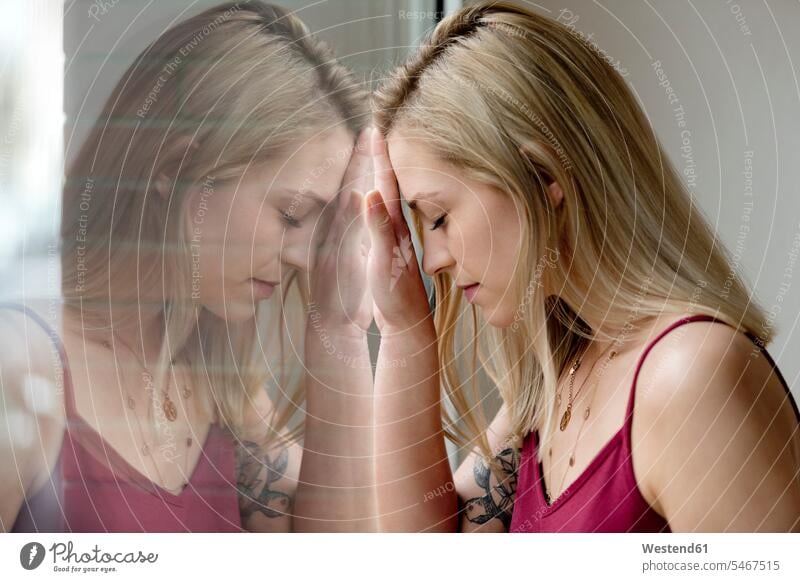 Profil einer blonden jungen Frau und ihr Spiegelbild auf einer Fensterscheibe Spiegelung Spiegelungen Profile blonde Haare blondes Haar Fensterscheiben weiblich
