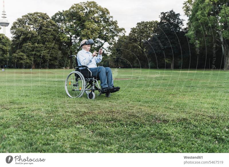 Älterer Mann sitzt im Rollstuhl in einem Park und benutzt eine Virtual-Reality-Brille entdecken entspannen relaxen sehen sehend sitzend entspanntheit relaxt
