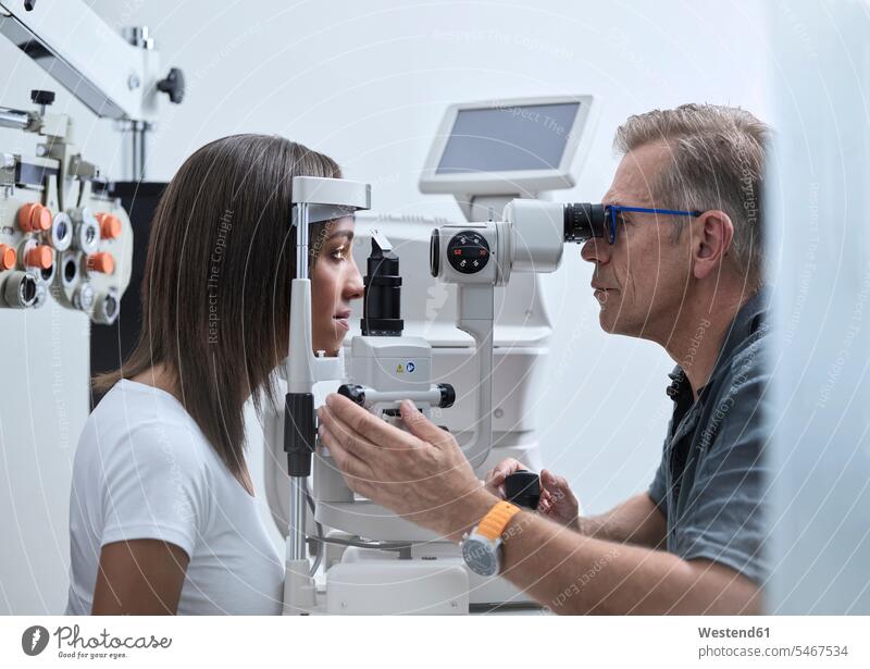 Optometristin untersucht das Auge einer jungen Frau Patientin Kranke Patientinnen überprüfen testen checken Untersuchung mustern Untersuchungen untersuchen