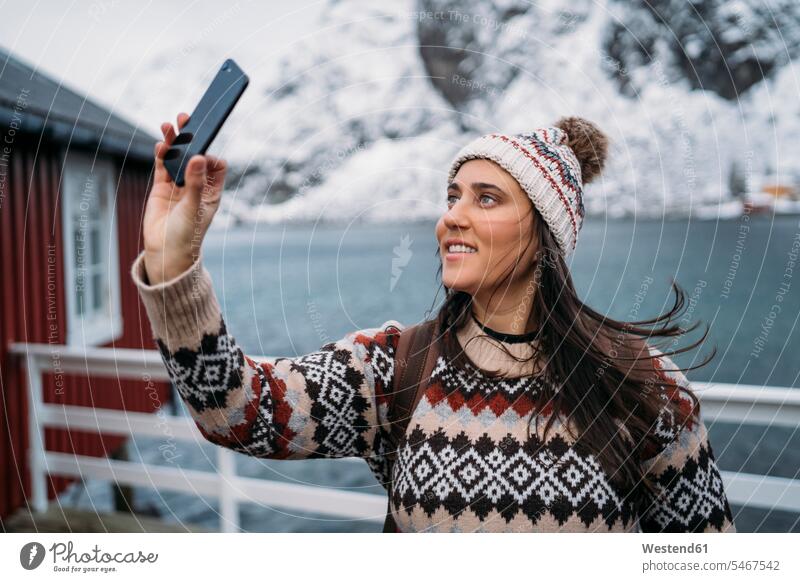 Tourist macht ein Selfie an der Küste, Lofoten, Norwegen Touristen Telekommunikation telefonieren Handies Handys Mobiltelefon Mobiltelefone Jahreszeiten