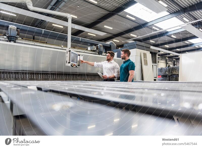 Zwei Männer schauen auf den Bildschirm in der Fabrikhalle Fabriken ansehen sprechen reden Produktionshalle Montagehalle Mann männlich Monitor Screen Monitore
