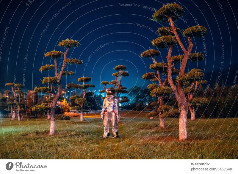 Spaceman stehend in einem Park bei Nacht nachts Raumfahrer Weltraumfahrer Astronaut Astronauten steht Parkanlagen Parks Raumfahrt Alien Außerirdische Aliens