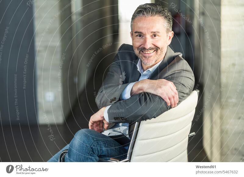 Porträt eines lächelnden reifen Geschäftsmannes, der auf einem Stuhl im Büro sitzt Job Berufe Berufstätigkeit Beschäftigung Jobs geschäftlich Geschäftsleben