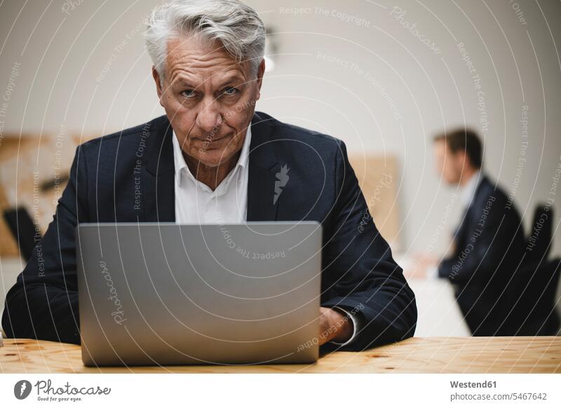 Älterer Geschäftsmann arbeitet am Laptop, sitzt mit Kollegen im Büro Job Berufe Berufstätigkeit Beschäftigung Jobs geschäftlich Geschäftsleben Geschäftswelt