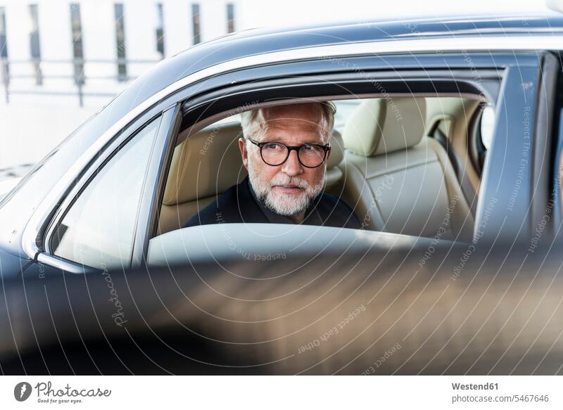 Ein reifer Geschäftsmann sitzt auf dem Rücksitz im Auto und schaut aus dem Fenster aus dem Fenster sehen durchs Fenster schauen aus dem Fenster schauen