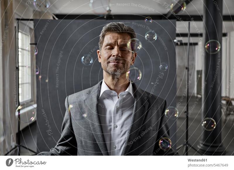Porträt eines reifen Geschäftsmannes mit Luftblasen vor schwarzem Hintergrund im Loft Lofts Blase Bläschen Blasen Blaeschen Kulisse Portrait Porträts Portraits