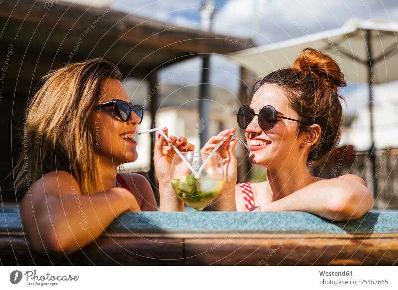 Zwei Frauen mit einem Getränk in einem Jacuzzi Freunde Kameradschaft Freundin Gläser Trinkglas Trinkgläser Strohhalme Trinkhalm Trinkhalme Badebekleidung