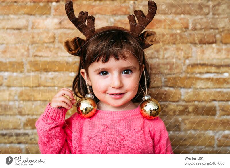 Porträt von lächelnden Kleinkind Mädchen trägt Rentiergeweih Stirnband und Weihnachtskugeln Spanien Christbaumkugel Christbaumkugeln glänzend glaenzend Glanz