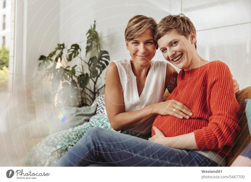 Porträt eines glücklichen lesbischen Paares, das den Bauch der werdenden Mutter berührt schwanger Schwangere schwangere Frau Glück glücklich sein glücklichsein