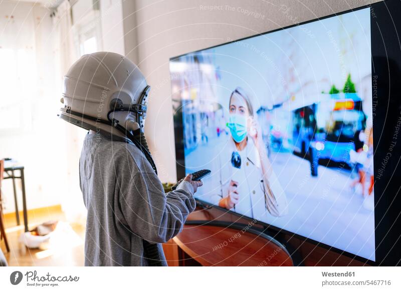 Junge mit Weltraumhelm sieht zu Hause stehend der Mutter der Journalistin im Fernsehen zu Farbaufnahme Farbe Farbfoto Farbphoto Spanien Innenaufnahme