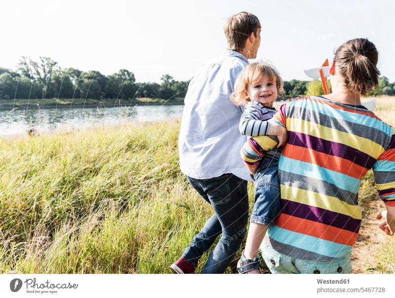 Glückliche Familie beim Spaziergang am Flussufer an einem schönen Sommertag Wiese Wiesen Sommerzeit sommerlich glücklich glücklich sein glücklichsein gehen