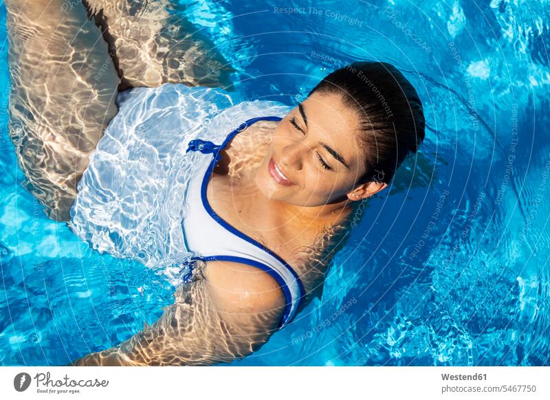 Porträt einer molligen jungen Frau, die sich im Schwimmbad entspannt Swimmingpool Swimmingpools Schwimmbecken Swimming Pool Swimming Pools weiblich Frauen
