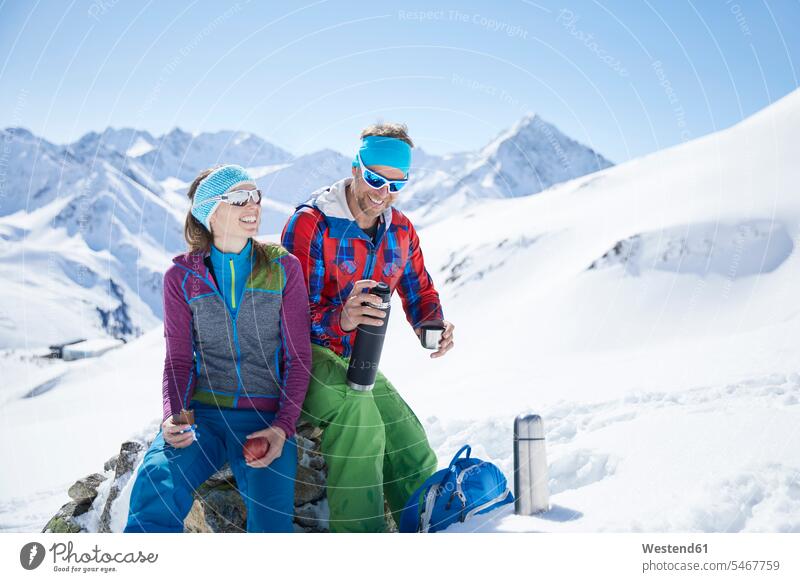Glückliche Skitourengeher machen eine Pause in den Bergen, Kühtai, Tirol, Österreich Brillen Sonnenbrillen sitzend sitzt winterlich Winterzeit freuen Frohsinn