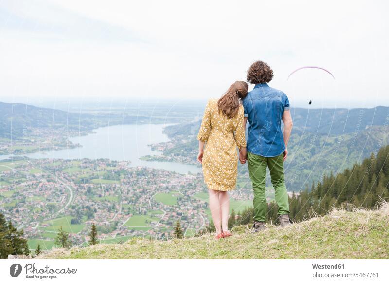 Mittelgroßes erwachsenes Paar hält sich an den Händen, während es die Landschaft vom Berggipfel aus betrachtet Farbaufnahme Farbe Farbfoto Farbphoto