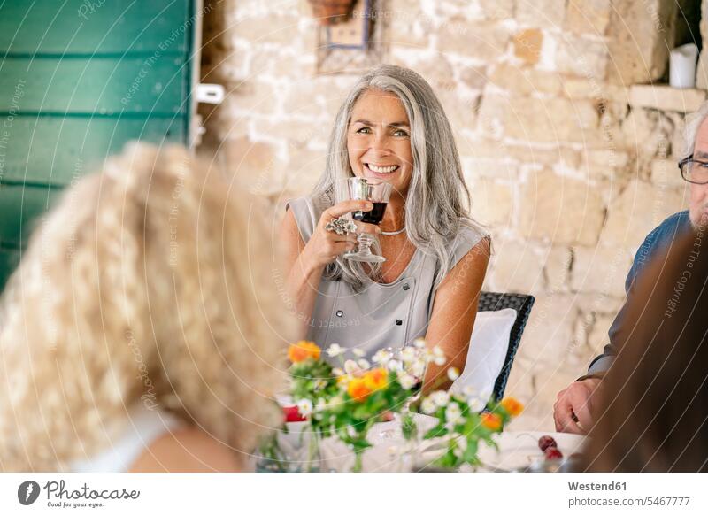 Porträt einer lächelnden Frau, die auf einer Familienfeier Wein trinkt weiblich Frauen Familienfest Familienfeste Familienfeiern Rotwein Rotweine trinken
