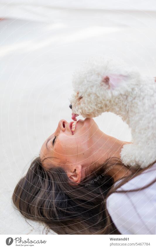 Glückliche junge Frau kuscheln mit Hund auf Dachterrasse Hunde schmusen knuddeln weiblich Frauen Dachterrassen liegen liegend liegt Haustier Haustiere Tier