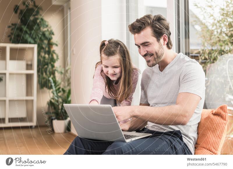 Junger Mann und kleines Mädchen surfen zusammen im Netz Websurfen Im Net surfen Surfen Regal Ablage Regale Wohnzimmer Wohnraum Wohnung Wohnen Wohnräume