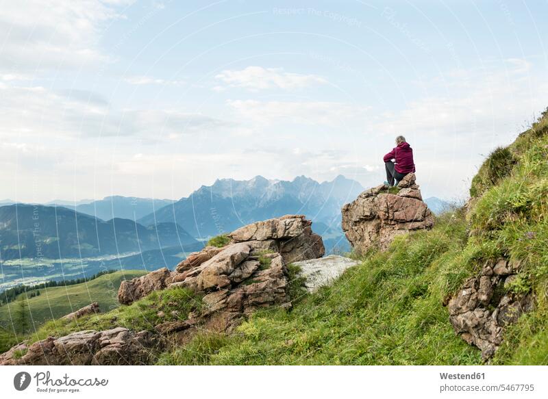 Österreich, Tirol, Fieberbrunn, Wildseeloder, Frau sitzt auf Stein mit Blick auf Berglandschaft sitzen sitzend Aussicht Ausblick Ansicht Überblick