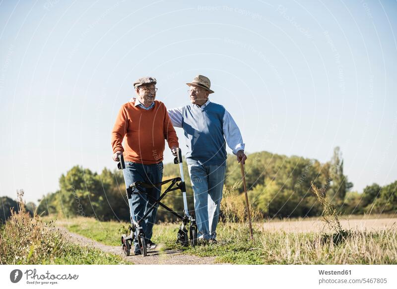 Alte Freunde bei einem Spaziergang in den Feldern mit Gehstock und Rollator, die über alte Zeiten reden Deutschland Alter Gemeinsamkeit zusammen gemeinsam