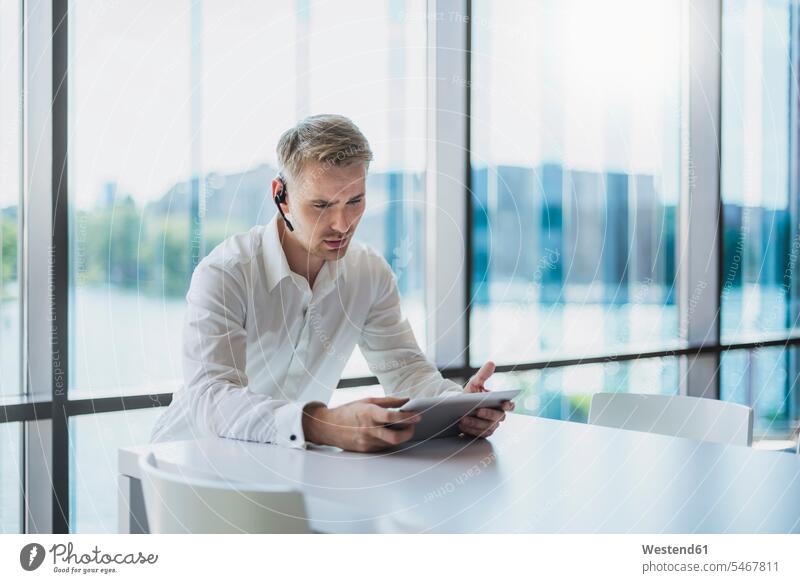 Geschäftsmann, der mit einem Headset telefoniert und ein digitales Tablet benutzt Job Berufe Berufstätigkeit Beschäftigung Jobs geschäftlich Geschäftsleben