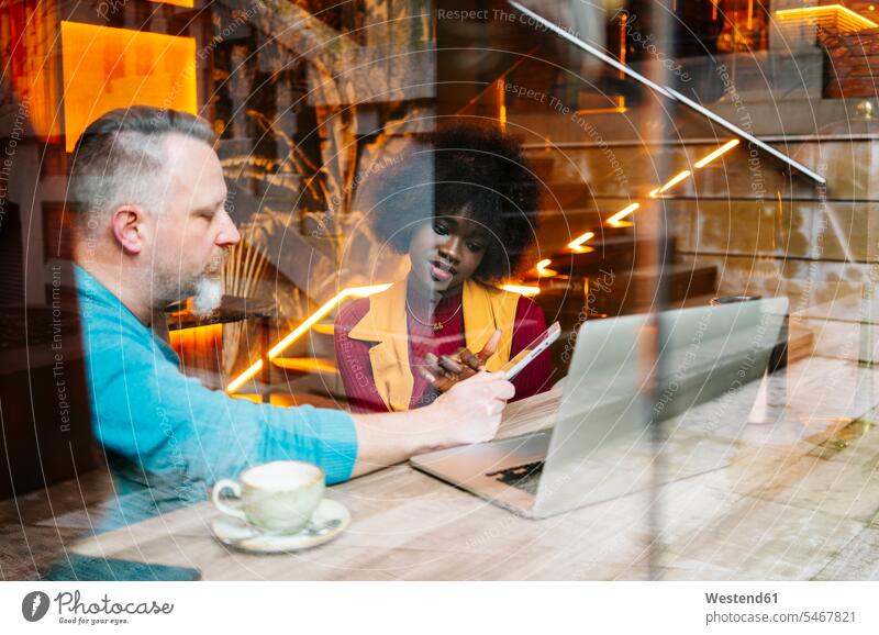Kollegen, die in einem Restaurant sitzen, über einen Wok diskutieren und ein digitales Tablet benutzen Leute Menschen People Person Personen Europäisch