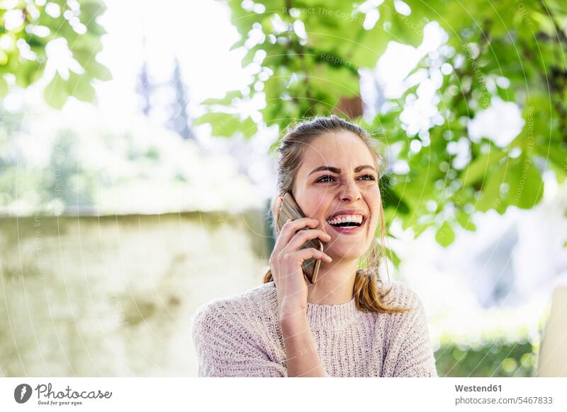 Porträt einer lachenden Frau am Telefon im Freien telefonieren anrufen Anruf telephonieren Smartphone iPhone Smartphones Portrait Porträts Portraits weiblich