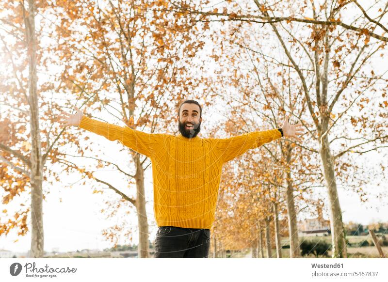 Junger Mann mit offenen Armen und glücklich in einem Park im Herbst morgens Morgen früh Frühe Freude freuen Vater Papas Väter Vati Vatis Papis aufgeschlossen