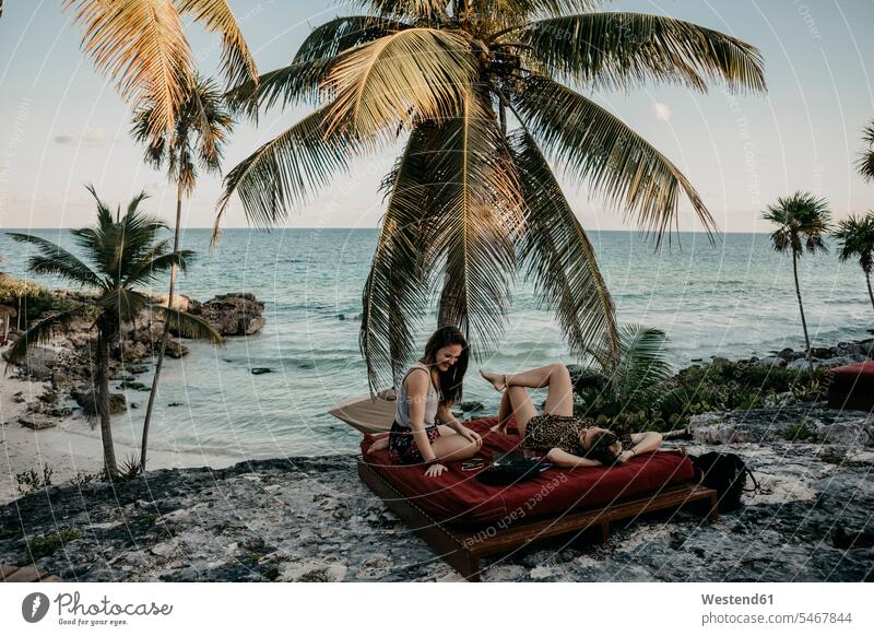Mexiko, Quintana Roo, Tulum, zwei glückliche junge Frauen entspannen am Strand Meer Meere Touristin Matratze steinig Erholung erholen Gemeinsamkeit zusammen