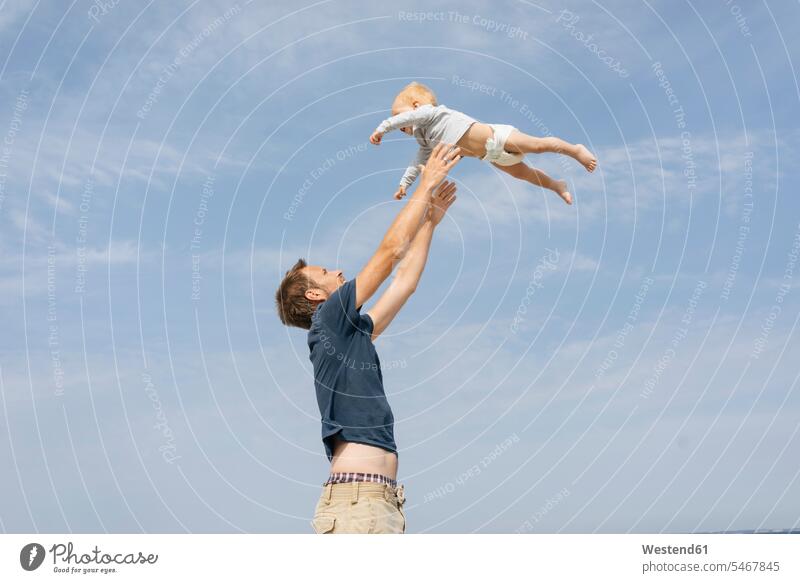 Deutschland, Timmendorfer Strand, Vater wirft Sohn in die Luft Spaß Spass Späße spassig Spässe spaßig Himmel Natur Hochgefühl Heiterkeit heiter Glücksgefühl