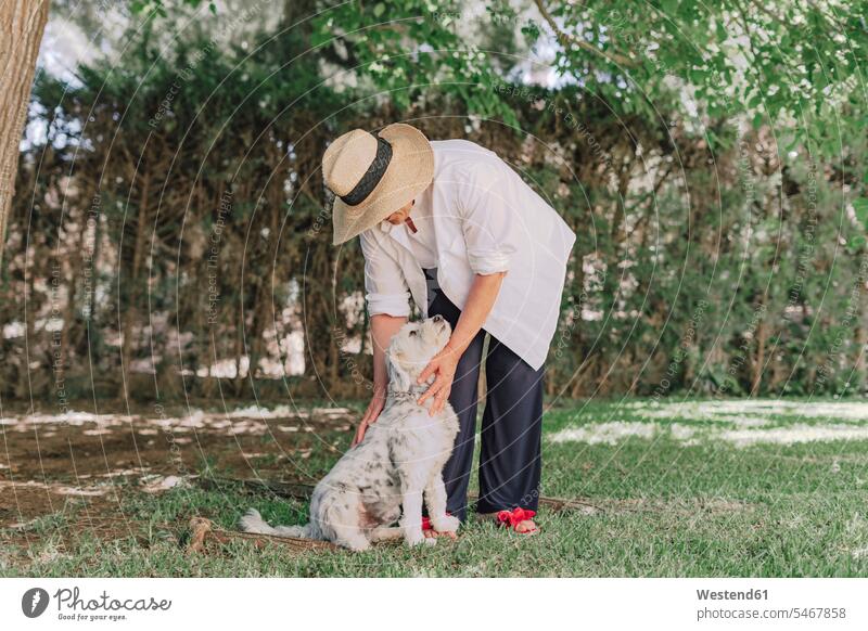 Ältere Frau mit Hut und Hund steht auf Grasland im Hof Farbaufnahme Farbe Farbfoto Farbphoto Spanien Freizeitbeschäftigung Muße Zeit Zeit haben Freizeitkleidung