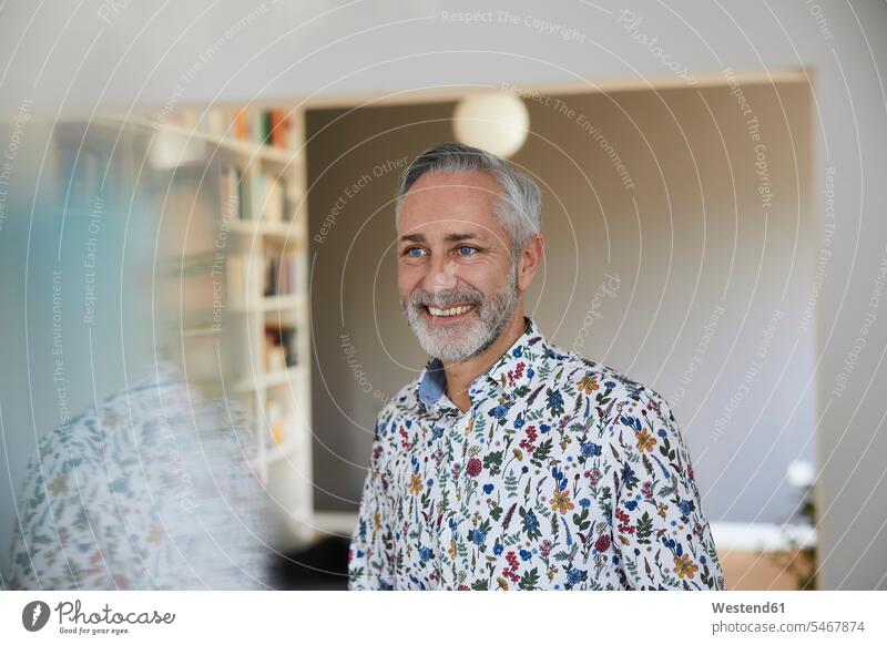 Porträt eines lächelnden reifen Mannes, der zu Hause ein gemustertes Hemd trägt Leute Menschen People Person Personen Alleinstehende Alleinstehender Singles