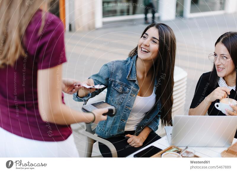 Junge Frau beim Bezahlen in einem Cafe Spanien Kartenlesegerät Kartenlesegeraet Beleg Belege bargeldlos überreichen ueberreichen uebergeben übergeben