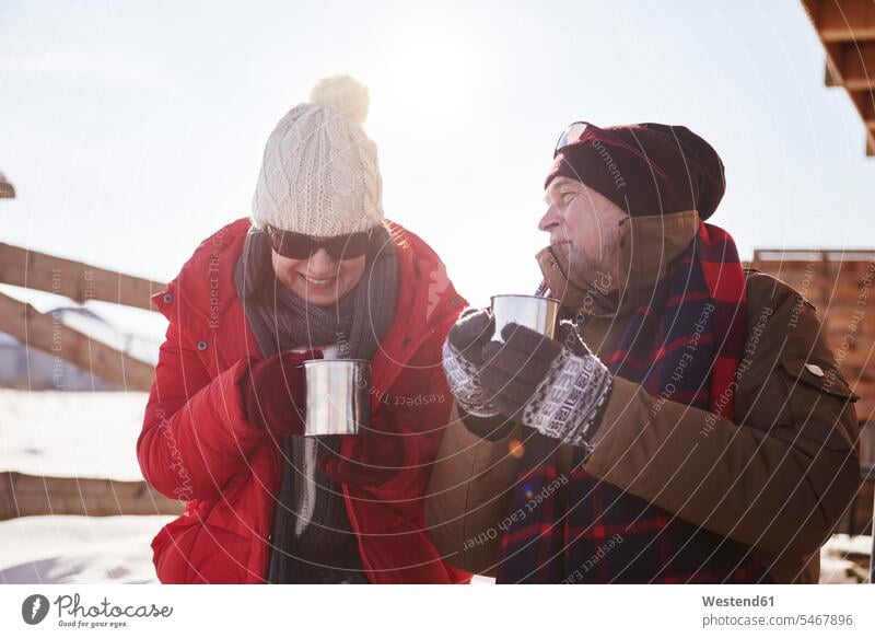 Glückliches reifes Paar mit heissen Getränken im Winter auf einer Berghütte im Freien glücklich glücklich sein glücklichsein Heißgetränk heißes Getränk
