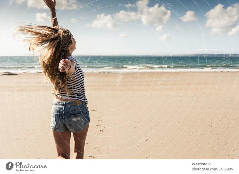 Glückliche junge Frau tanzt am Strand drehen tanzen tanzend wirbeln Beach Straende Strände Beaches junge Frauen weiblich Erwachsener erwachsen Mensch Menschen