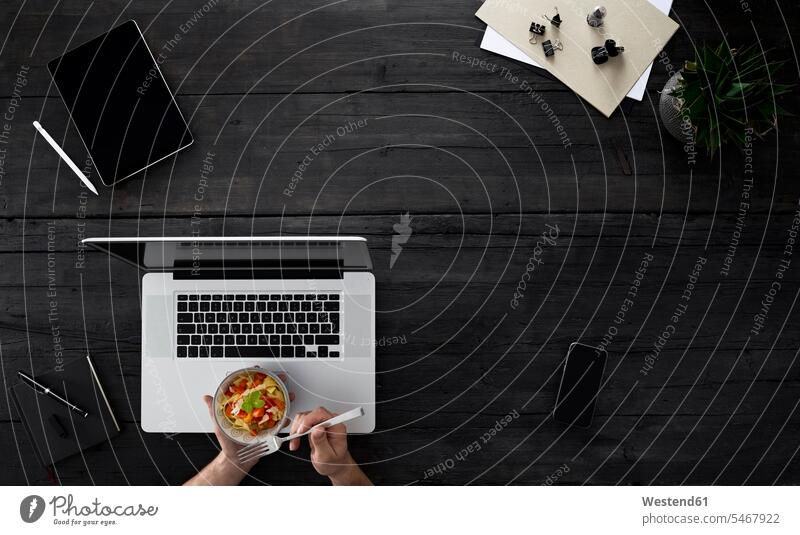 Person mit Laptop und Snack am Schreibtisch sitzend essen essend Überlastung Überforderung überarbeitet Überarbeitung überfordert überlastet Salat Salate Gabel
