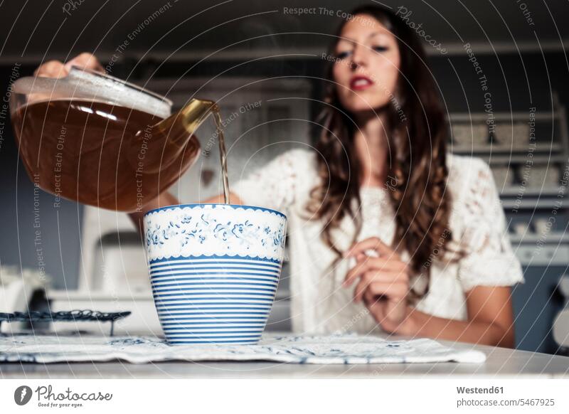 Junge Frau gießt Tee in Tasse Tischdecken Tischtuch Tischtuecher Tischtücher Farben Farbtoene Farbton Farbtöne blaue blauer blaues weiss weiße weißer weißes