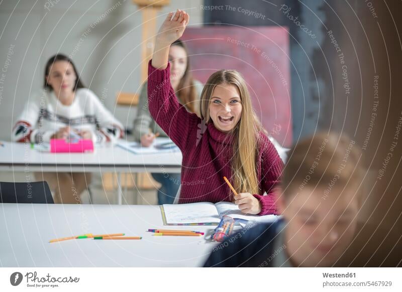 Glückliches Teenager-Mädchen hebt die Hand in der Klasse Jugendliche Heranwachsende Pubertierende melden sich melden glücklich glücklich sein glücklichsein