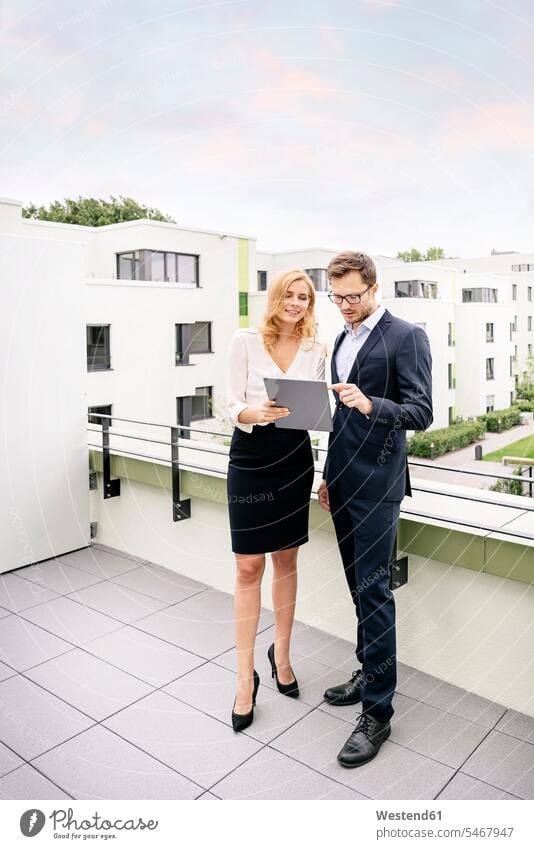 Immobilienmakler, der mit einem Kunden auf einem Balkon steht und auf ein digitales Tablet schaut stehen stehend Geschäftsfrau Geschäftsfrauen Businesswomen
