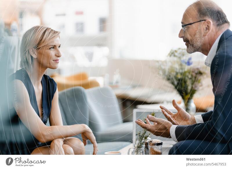 Ein Geschäftsmann und eine Geschäftsfrau treffen sich in einem Café und diskutieren über die Arbeit Leute Menschen People Person Personen Europäisch Kaukasier
