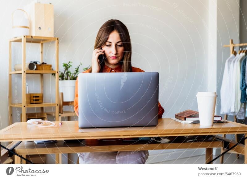 Modedesignerin sitzt am Schreibtisch im Home-Office und telefoniert Job Berufe Berufstätigkeit Beschäftigung Jobs geschäftlich Geschäftsleben Geschäftswelt