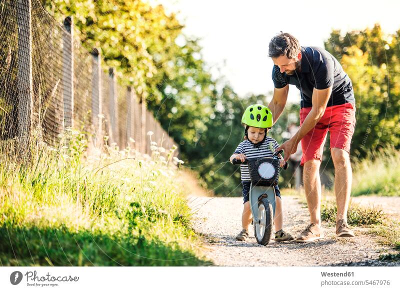 Vater lehrt kleinen Sohn Fahrrad fahren Söhne radfahren fahrradfahren radeln Papas Väter Vati Vatis Papis Bikes Fahrräder Räder Rad lehren unterrichten